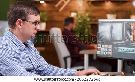 Focused videographer producer working at movie production editing film design using company software in creativity office. Photographer man developing footage effects. Multimedia industry