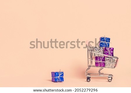Small decorative trolley with present boxes on pastel background. Christmas or birthday gift. Sales and shopping concept.  Image is with copy space