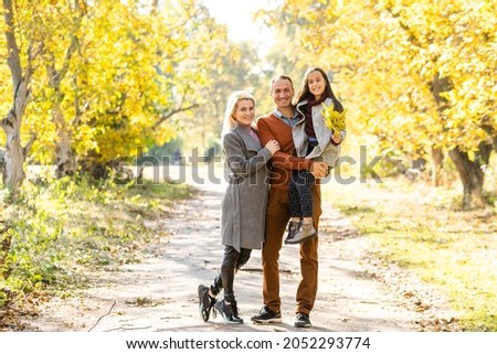 Picture of lovely family in autumn park, young parents with nice adorable kid playing outdoors, have fun on backyard in fall, happy family enjoy autumnal nature