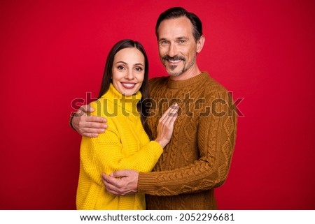 Photo of two peaceful positive persons hugging have good mood beaming smile isolated on red color background