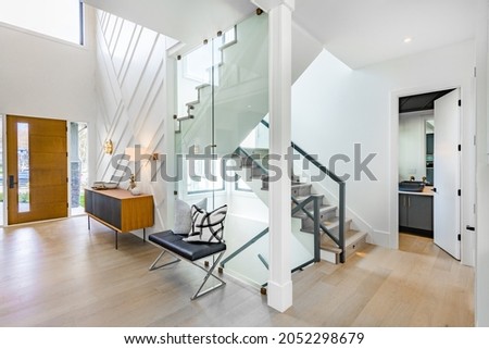 Entry hall and foyer with glass walls stairs console table bench and wooden door Royalty-Free Stock Photo #2052298679