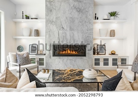 contemporary living room with open concept view through to dining room kitchen and a marble fireplace with gas fire Royalty-Free Stock Photo #2052298793