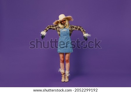 Full body young woman with Halloween makeup mask in straw hat scarecrow costume stand posing like bugaboo with closed eyes isolated on plain dark purple background studio Celebration holiday concept.
