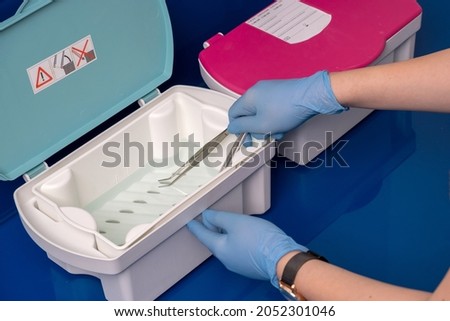 Nurse putting dental equipment in disinfectant box in dental clinic