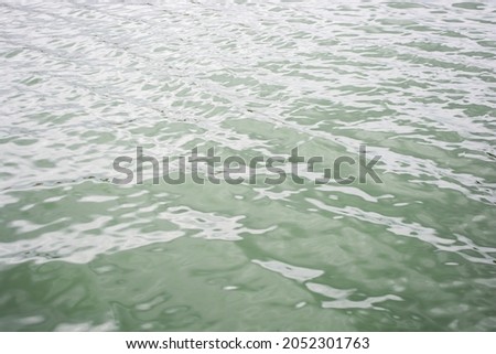 River green water covered with small waves glistening in the sunlight.
