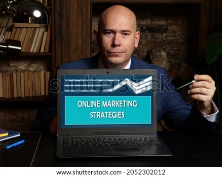  ONLINE MARKETING STRATEGIES inscription on the screen. Man office worker looking at screen of laptop 
