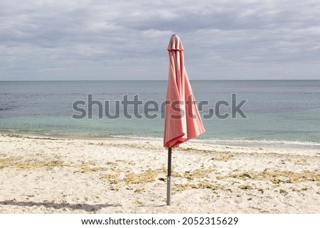 Red single umbrella on empty sea beach end of summer season concept