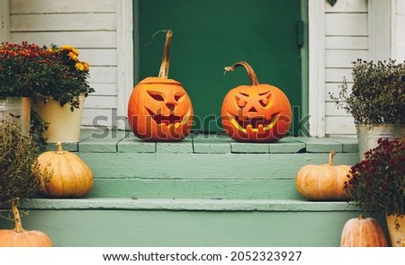 Staircase autumn decor. House entrance with halloween pumpkin decoration on wooden stairs, two jack o lanterns with spooky faces on porch of apartment building during all hallows eve Royalty-Free Stock Photo #2052323927