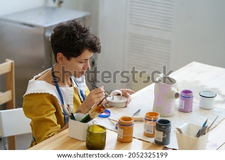 Art and entertainment: young girl study ceramics craftsmanship after work to start small business with pottery studio and shop of handmade earthenware decor for house and kitchenware. Artist at work