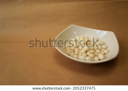 white small indonesian snack called pilus snacks on little  bowl isolated with bwrown paper background