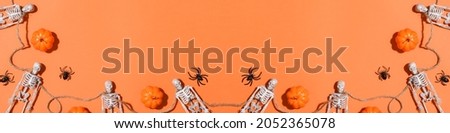 Halloween background with skeletons and pumpkins and spiders forming a frame. Flat layout, top view, place to copy.