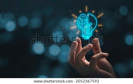 Hand holding drawing virtual lightbulb with brain on bokeh background for creative and smart thinking idea concept. Royalty-Free Stock Photo #2052367592