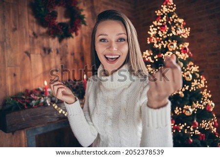 Photo of charming sweet young woman dressed knitted sweater showing korean love sign smiling indoors room home house