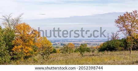 A scenic  landscape view from the top of a hill at the start of autumn