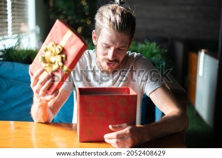 young male person opens red present box on christmas