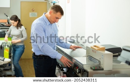 Man uses plotter in small printing shop. High quality photo