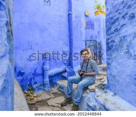 Young photographer taking pictures in a blue house in Jodhpur, India.