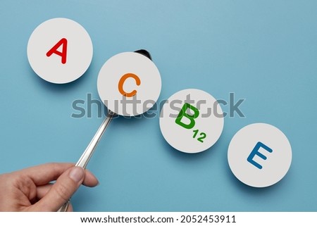 Paper circles with inscriptions: vitamin A, B, C, E. Lack of vitamin C in the human body Royalty-Free Stock Photo #2052453911