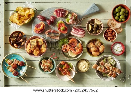 Top view of assorted snacks with kebabs or tapas placed near seafood and fried chicken served in bowls on table with assorted sausages Royalty-Free Stock Photo #2052459662
