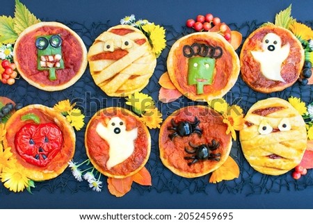 Halloween mini pizza with cheese, olives and ketchup. Decorated mummy, ghost, spiders, zombie, pumpkin. Funny crazy food for kids.
