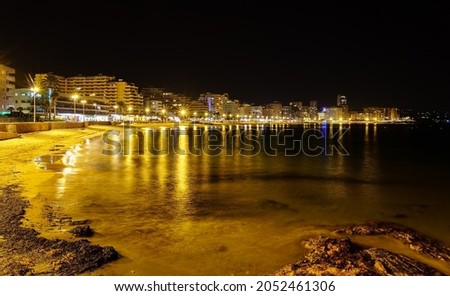 Beach at night with illuminated buildings and reflections of lights in the water. Calpe Alicante.