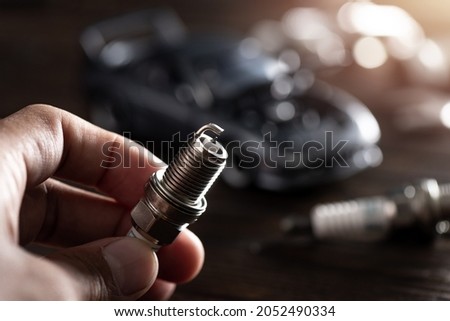 Close up new automotive spark plug. Car maintenance concept.  Royalty-Free Stock Photo #2052490334