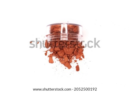 Creative photo of cosmetic swatches. Broken eye shadows in bronze colour and on a white background 