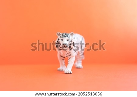 the tiger, symbol of 2022 year. plastic white toy figure tiger on a red background