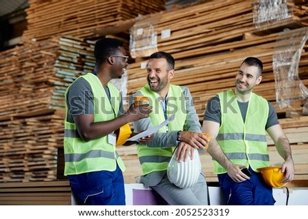 Happy workers having fun while talking with their manager on coffee break at lumber distribution warehouse. Royalty-Free Stock Photo #2052523319