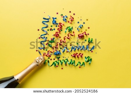 Creative flat lay composition with bottle of champagne and space for text on color background. Champagne bottle with colorful party streamers. holiday or christmas concept.