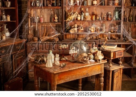 Halloween background Shelves with alchemy tools Skull spiderweb bottle with poison candles Witcher workspace Scarry room Royalty-Free Stock Photo #2052530012