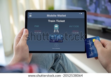 male hands holding computer tablet with train ticket application on screen and credit card background of room
