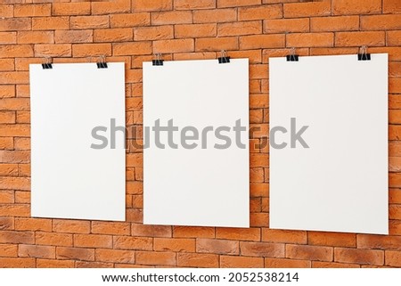 Blank posters hanging on brick wall