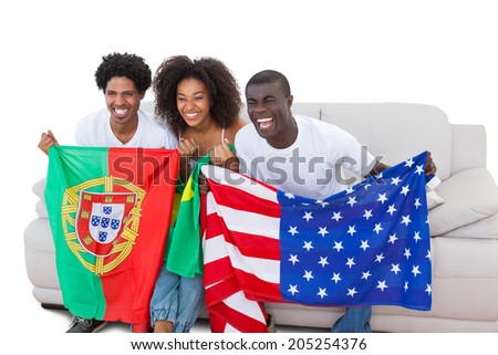 Cheering football fans holding flags on the sofa on white background
