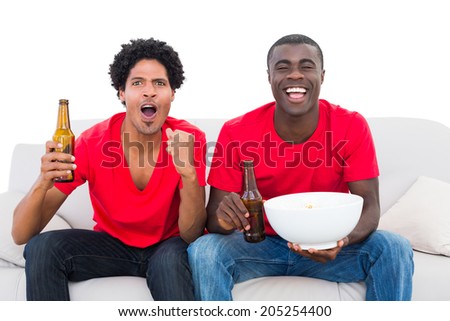 Football fans in red cheering on the sofa with beers and popcorn on white background