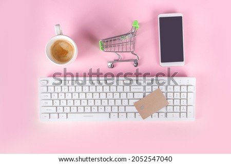 Christmas sale black friday background with shopping red green paper bags, shopping cart, bank card, computer keyboard, smartphone on pink colorful background top view copy space