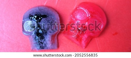 Halloween or día de muertos composition: ice skulls in red and black surrounded by insects on a red background