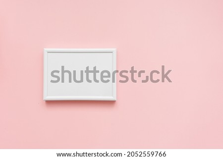 A white blank picture frame on a pink background. Top view. 