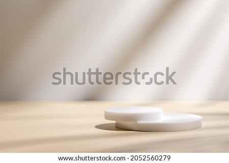 Abstract minimal nature scene - empty stage and circle podiums on beige background and soft shadows of tree leaves. Pedestal for cosmetic product and packaging mockups display presentation