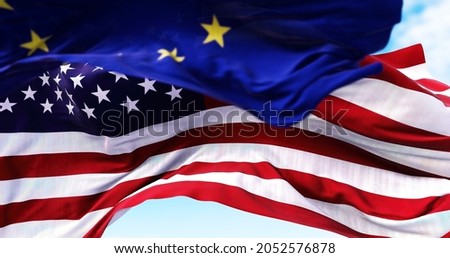 The national flag of the United states of America waving in the wind with the European Union flag blurred in the foreground. Politics and finance. Global finance, International relations and diplomacy