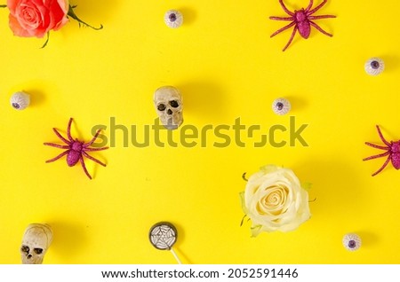 Colorful Halloween concept with skulles, spiders and eyeballs on vivid yellow background. Creative spooky celebration idea.