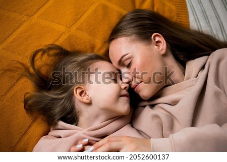 mom and daughter are lying on a blanket on the bed and hugging