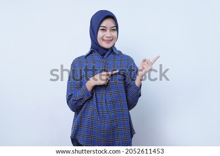 Smiling young woman wearing hijab showing peaceful gesture isolated on white wall