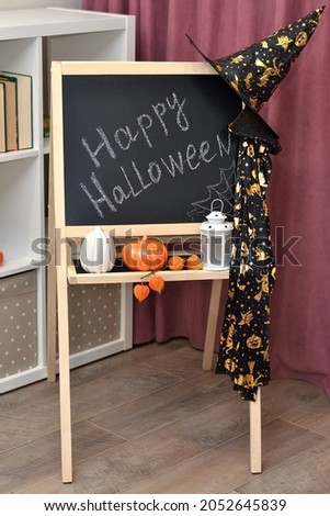 happy Halloween. the inscription on the school blackboard. school holiday halloween. witch's hat and cloak, orange pumpkin.