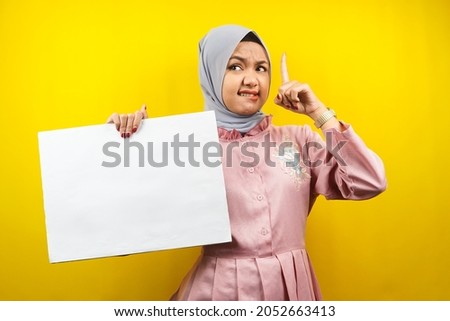 Pretty young muslim woman getting idea, hand holding blank empty banner, placard, white board, blank sign board, white advertisement board, presenting something in copy space, promotion