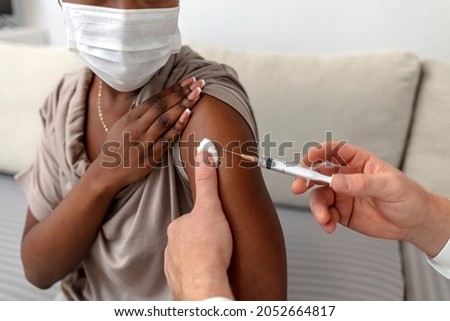 Epidemic outbreak, covid-19 immunization. Professional doctor or nurse giving flu or COVID injection to patient, adult Caucasian male in uniform vaccinate young woman in protective mask.