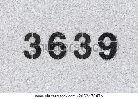 Black Number 3639 on the white wall. Spray paint. Number three thousand six hundred thirty nine.