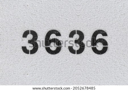 Black Number 3636 on the white wall. Spray paint. Number three thousand six hundred thirty six.