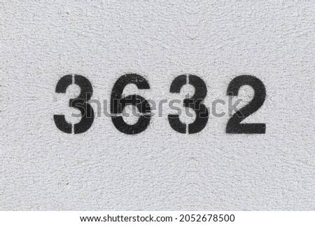 Black Number 3632 on the white wall. Spray paint. Number three thousand six hundred thirty two.