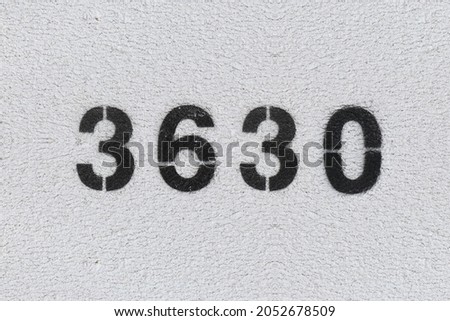 Black Number 3630 on the white wall. Spray paint. Number three thousand six hundred thirty.